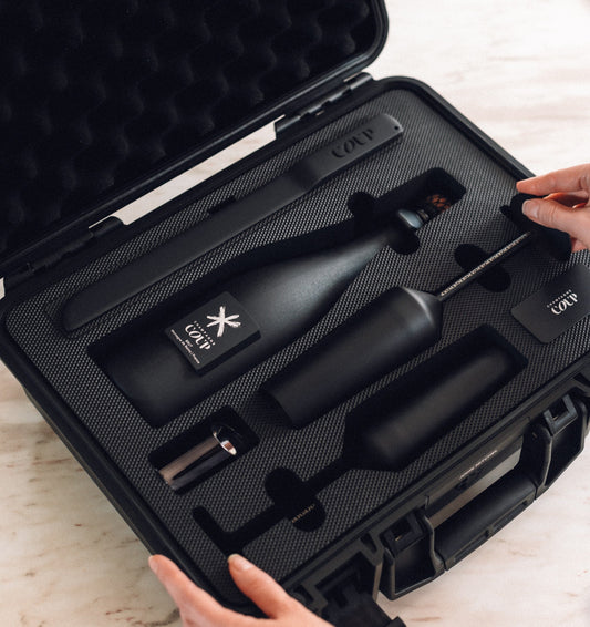 Open COUP Champagne gift set with matte black bottle, flutes, saber, and custom case.